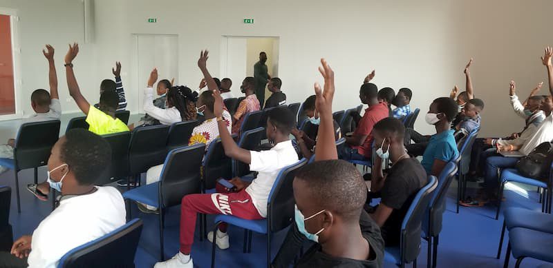 A group of students in a classroom with their hands raised